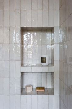 a white tiled bathroom with shelves and toiletries