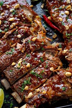 ribs covered in bbq sauce and garnished with peanuts, limes, and cilantro