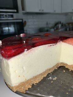 a cheesecake with strawberries on top is sitting on a metal pan in the kitchen