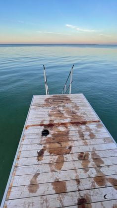 the end of a dock with water and sky in the background