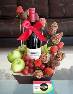 a bottle of wine sitting on top of a table filled with fruit and candys