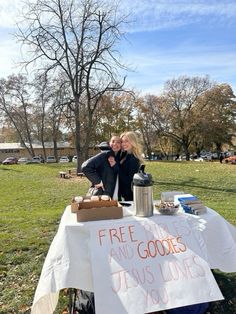 a man and woman kissing in front of a sign that reads free drinks and goodies jesus loves you