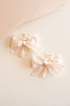 The Lindsay Chiffon Bow and Clear Gemstone Earrings exude a captivating charm, combining delicate chiffon bows with sparkling clear gemstones for an enchanting accessory that effortlessly elevates any ensemble.