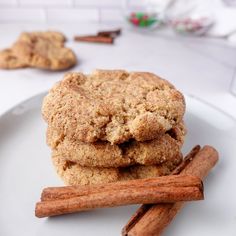 cinnamon cookies stacked on top of each other with cinnamon sticks next to them and two pieces of cinnamon in the background