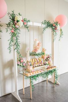 a baby shower with flowers and balloons on the table, in front of a white wall