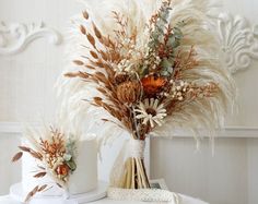 two vases filled with dried flowers on top of a table