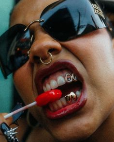 a woman with piercings on her tongue and wearing sunglasses