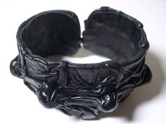 a close up of a black bracelet on a white surface