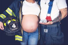 a pregnant firefighter holding a camera next to a man in a fireman's uniform