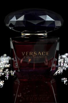 a bottle of perfume sitting on top of a black table covered in crystal stones and sparkles