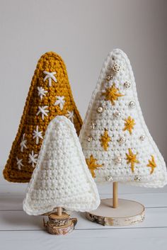 three crocheted christmas trees sitting on top of a white table next to each other