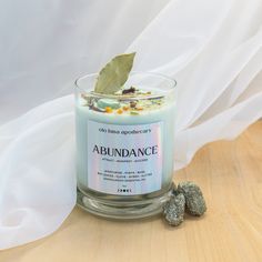 a candle with a green leaf on top next to some rocks and a white cloth