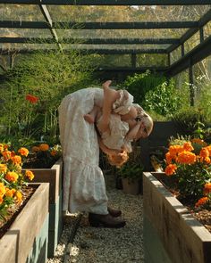 a woman bending over in a garden filled with flowers