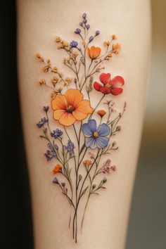 Colorful wildflower tattoo on forearm with red, blue, and orange blossoms. Roses And Wildflowers Tattoo, Beautiful Colorful Tattoos, Flower Tattoos For Women Color, Wildflower Garden Tattoo, Prairie Flower Tattoo, Flowers That Represent Strength, Spring Flowers Tattoo, Sunflower And Wildflower Tattoo, Flower Growing Tattoo