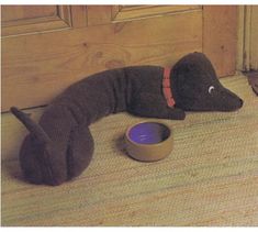 a stuffed animal laying on the floor next to a dog bowl and cat toy in front of a wooden door