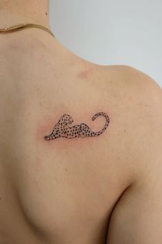 the back of a woman's shoulder with a cheetah tattoo on it