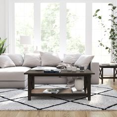 a living room filled with furniture and a white rug on top of a hard wood floor