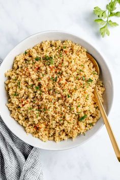 a white bowl filled with rice and garnished with parsley next to a wooden spoon