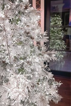 a white christmas tree in front of a window with snow flakes on the branches