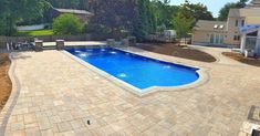 a backyard with a swimming pool surrounded by landscaping