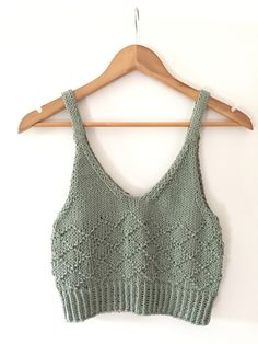 a green crop top hanging on a wooden hanger