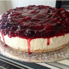 a cheesecake covered in blueberry sauce on top of a glass plate