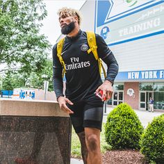 a man with a beard and black shorts is standing in front of a gym building