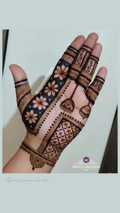 a person's hand with henna tattoos and flowers on the palm, holding it up