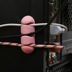 a pink and white device connected to a black wall with wires attached to it's sides