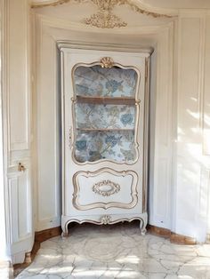 an antique china cabinet in the corner of a room with white walls and marble flooring