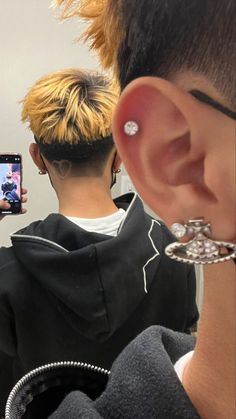 a person taking a selfie in front of a mirror with ear piercings on