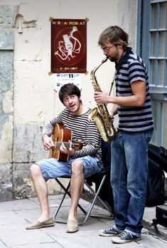 two men are playing instruments on the street