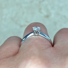 a person's hand holding a diamond ring