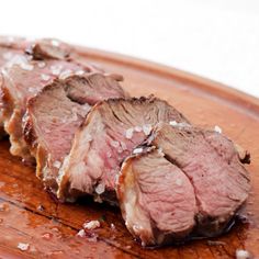 two pieces of meat sitting on top of a wooden cutting board