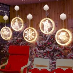 christmas decorations are hanging from the ceiling in front of a decorated tree and red chairs