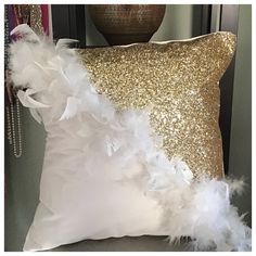 a gold and white pillow with feathers on it next to a vase filled with flowers