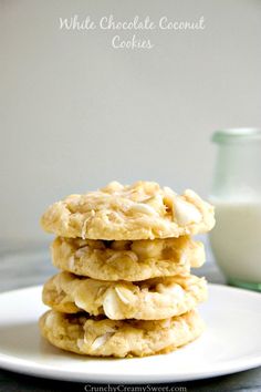 white chocolate coconut cookies stacked on top of each other with a glass of milk in the background