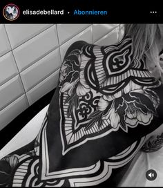 the back of a woman's body covered in black and white tattoos