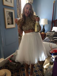 a woman in a gold top and white tulle skirt standing in a blue room