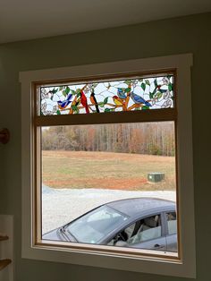 a car is parked in front of a window that has stained glass birds on it