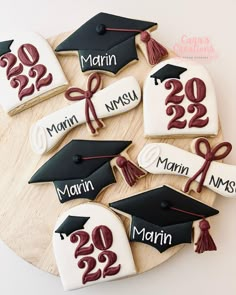 decorated cookies with graduation caps and tassels are arranged on a wooden platter