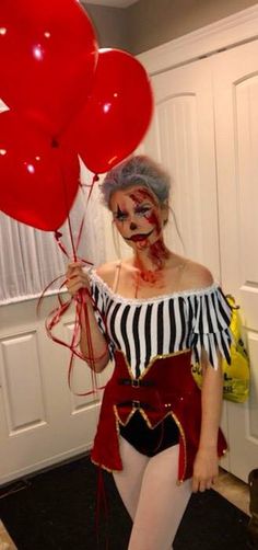 a woman dressed as a clown holding red balloons