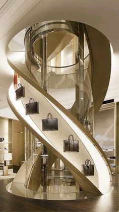 a spiral staircase in a luxury hotel with bags on the bottom and handbags hanging from it