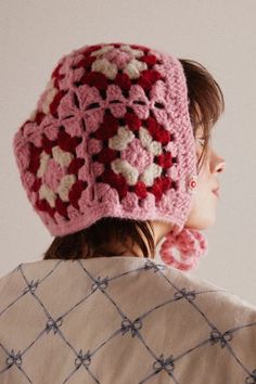 a woman wearing a pink crocheted hat with flowers on the top and back