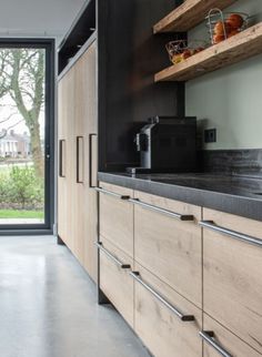 a kitchen with wooden cabinets and black counter tops next to a sliding glass door that leads outside