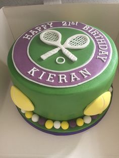 a green birthday cake with tennis rackets and balls on it's side in a box