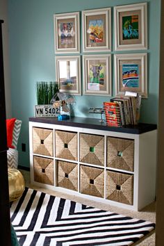 a room with pictures on the wall and a rug in front of it that has several drawers