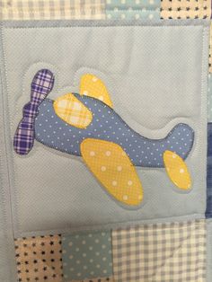 a blue and yellow quilt with an airplane appliqued on the front side