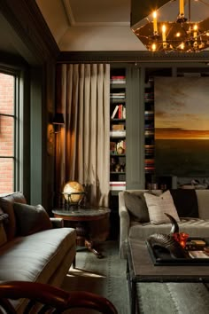 a living room filled with furniture and a painting hanging on the wall above it's windows