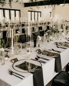 the tables are set up with black and white place settings for an elegant dinner party